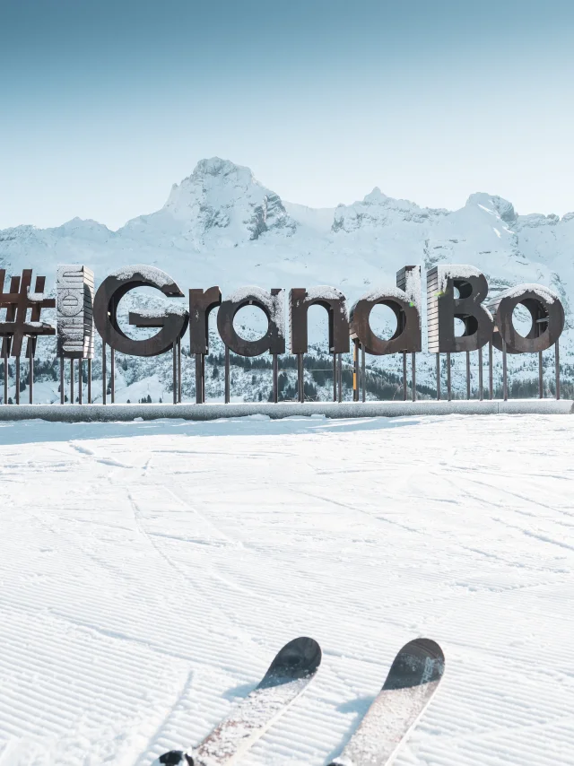 wooden letters with frost form the word mongrandbo in front of the snow-covered aravis range