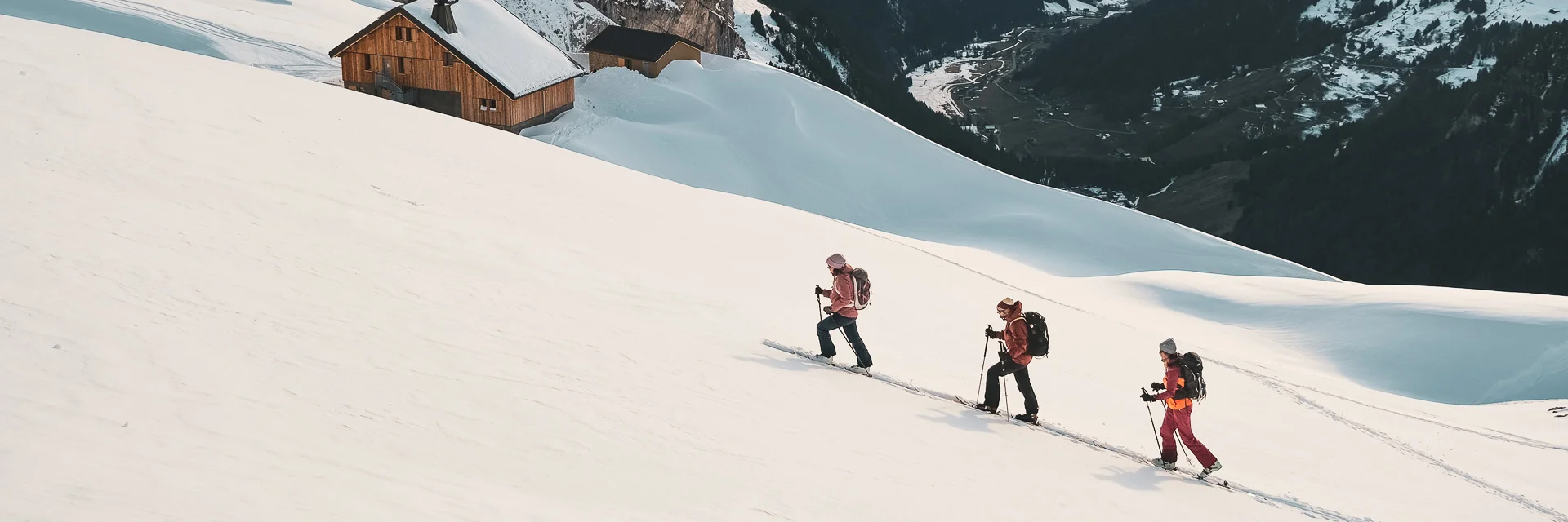 Randonneurs skieurs avançant dans la neige, refuge Gramusset et vallée du Bouchet en arrière-plan.