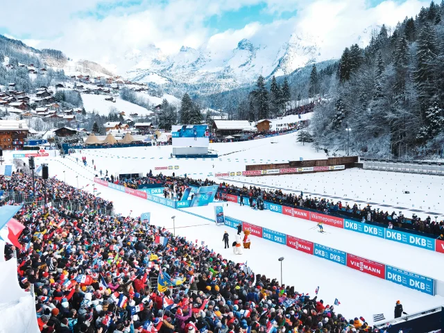 Vue aérienne du stade Sylvie Becaert dans un décor enneigé lors de la Coupe du monde de Biathlon Annecy-Le Grand-Bornand 2024. Nous pouvons voir la ferveur du public dans les gradins.