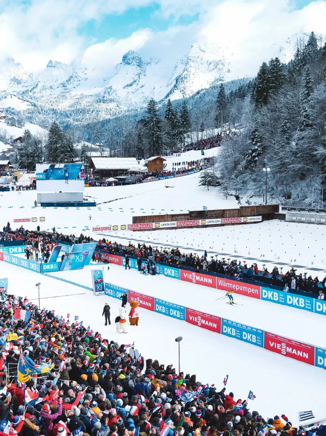 Vue aérienne du stade Sylvie Becaert dans un décor enneigé lors de la Coupe du monde de Biathlon Annecy-Le Grand-Bornand 2024. Nous pouvons voir la ferveur du public dans les gradins.