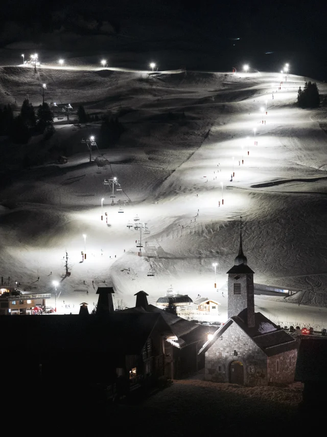 Night view of the Grand-Bornand ski area illuminated, with the emblematic church in the foreground.