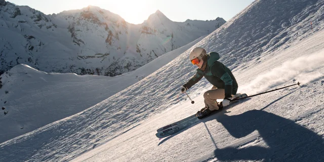 Une skieuse alpine dévalant une piste avec pour toile de fond, la chaîne des Aravis