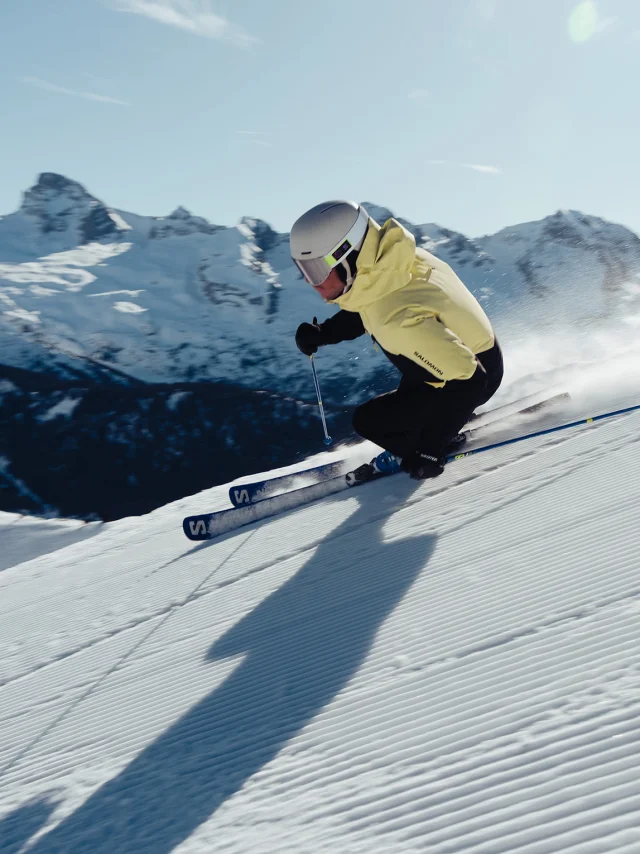 Skieur alpin dévalant la piste 2000 avec comme toile de fond, la chaîne des Aravis et la pointe Percée