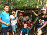 groupe d'enfants souriants dans une cabane faite de branchage
