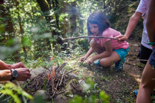 petite fille qui allume un feu de bois en forêt
